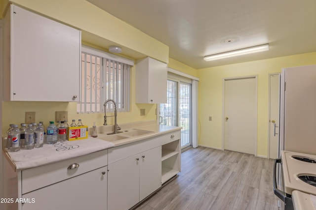 kitchen with white range with electric stovetop, light countertops, white cabinetry, open shelves, and a sink