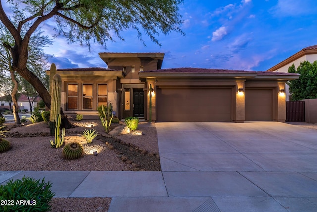 prairie-style house with a garage, stucco siding, a tiled roof, and concrete driveway
