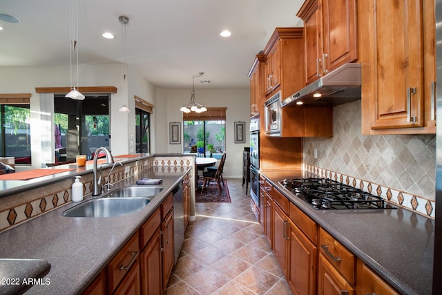kitchen featuring a notable chandelier, appliances with stainless steel finishes, a sink, decorative backsplash, and under cabinet range hood