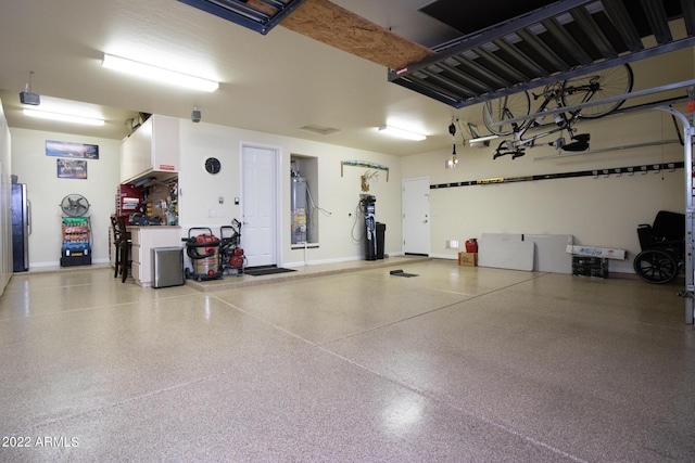 garage with baseboards, a garage door opener, gas water heater, and freestanding refrigerator