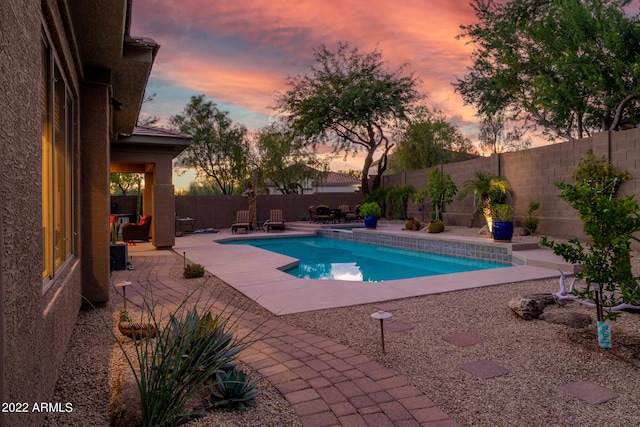 pool at dusk featuring a patio, a fenced in pool, and a fenced backyard