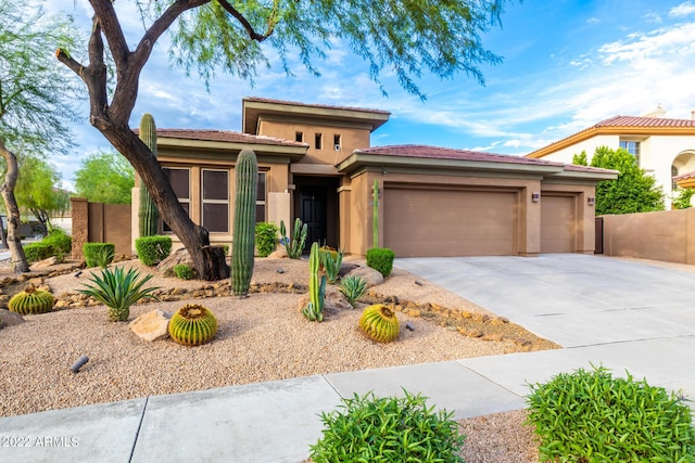 prairie-style home with fence, a garage, stucco siding, a tiled roof, and driveway