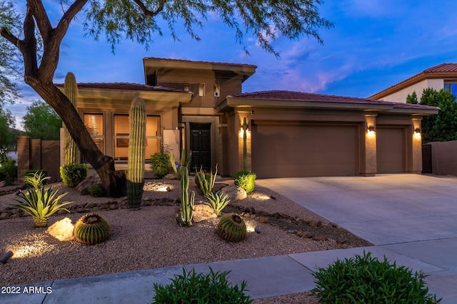 prairie-style home featuring a garage, fence, stucco siding, driveway, and a tile roof