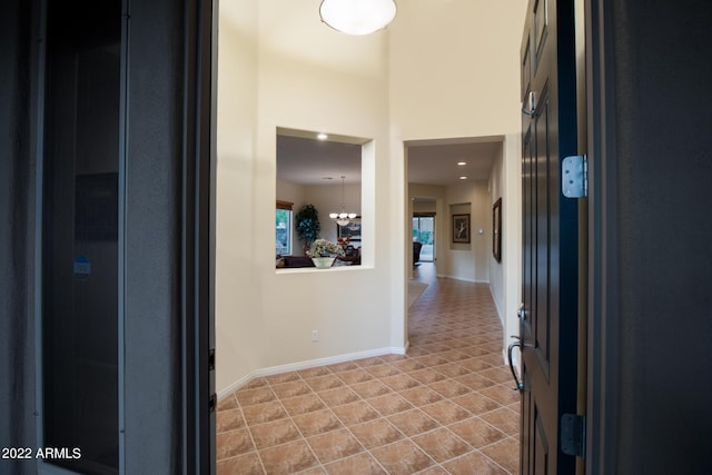 hall with baseboards, a notable chandelier, and light tile patterned floors