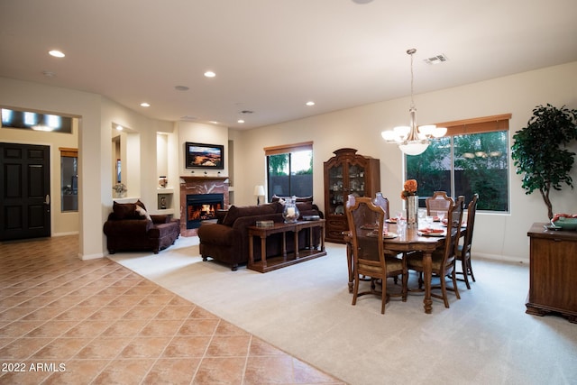 dining area with an inviting chandelier, light carpet, a premium fireplace, recessed lighting, and visible vents