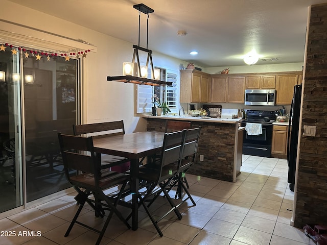 kitchen featuring hanging light fixtures, black appliances, kitchen peninsula, and light tile patterned flooring