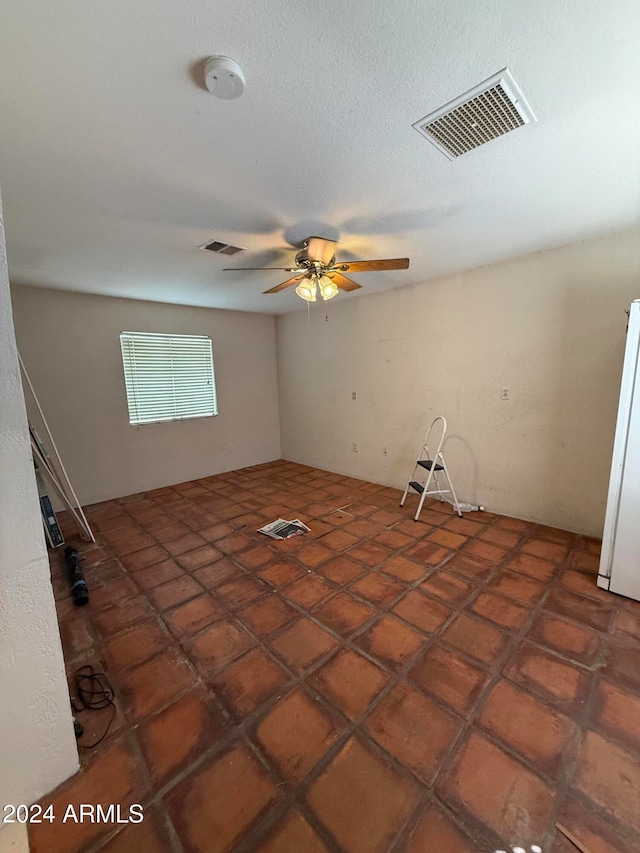 spare room featuring dark tile patterned flooring and ceiling fan