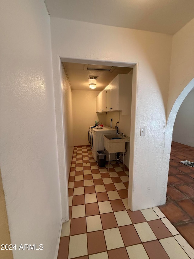 hall with sink, washing machine and clothes dryer, and light tile patterned floors