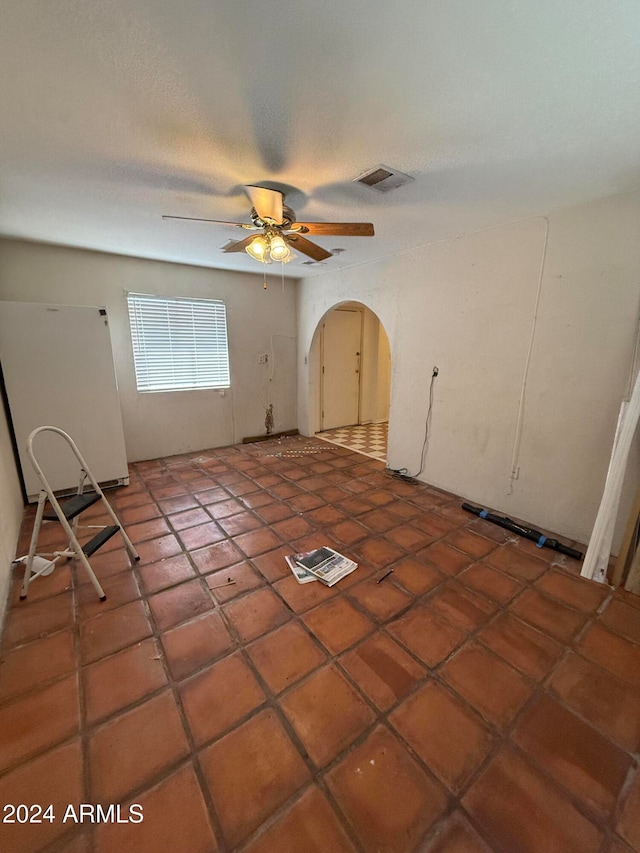 tiled empty room featuring ceiling fan