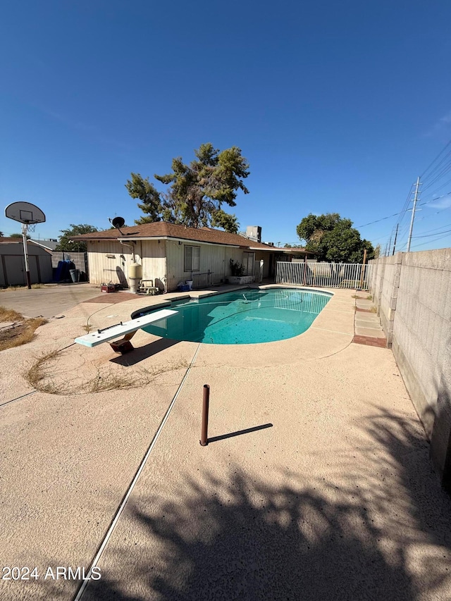 view of swimming pool featuring a patio and a diving board