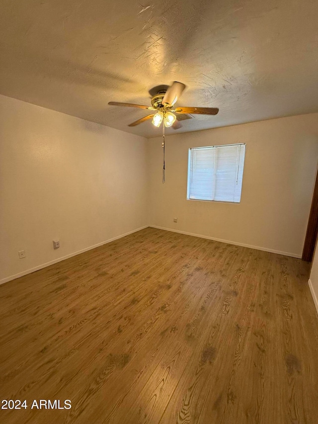 empty room with ceiling fan, wood-type flooring, and a textured ceiling