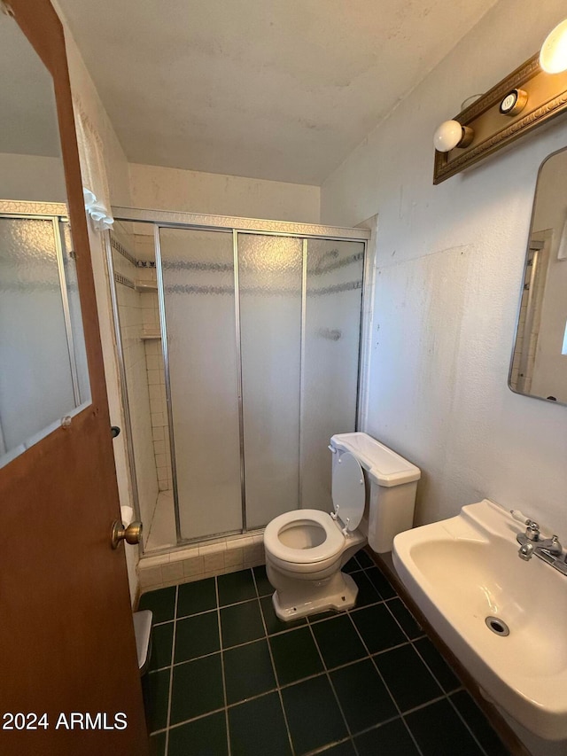 bathroom featuring toilet, walk in shower, sink, and tile patterned floors