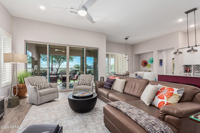 living room featuring light hardwood / wood-style floors, ceiling fan, and sink