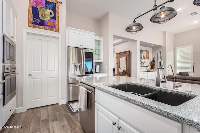 kitchen with light stone countertops, dark hardwood / wood-style flooring, stainless steel appliances, sink, and white cabinetry