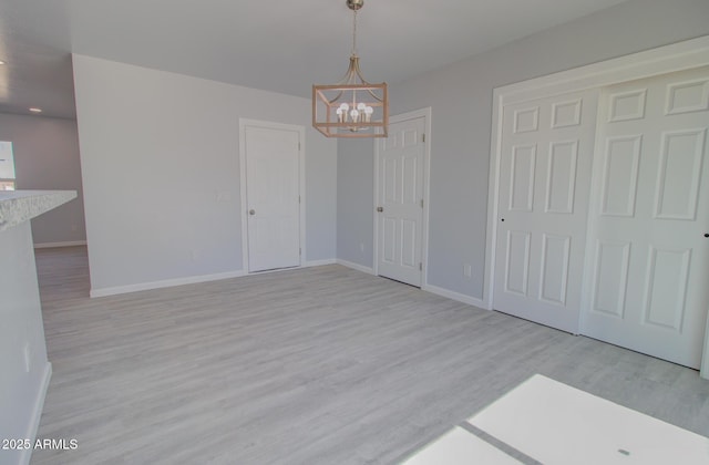 interior space featuring wood finished floors, baseboards, and a chandelier