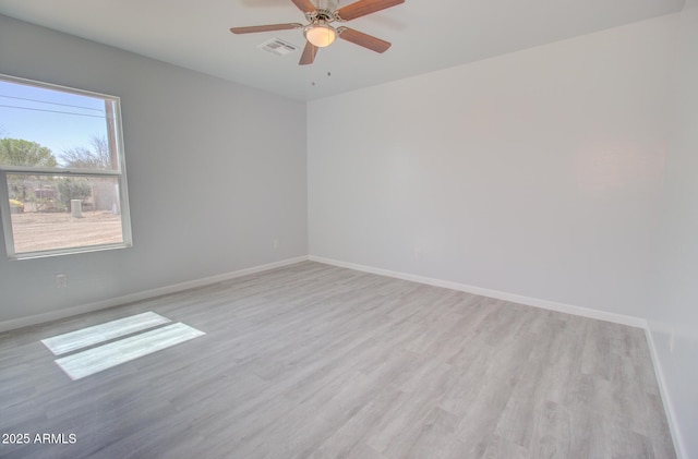 spare room with visible vents, light wood-style flooring, baseboards, and ceiling fan