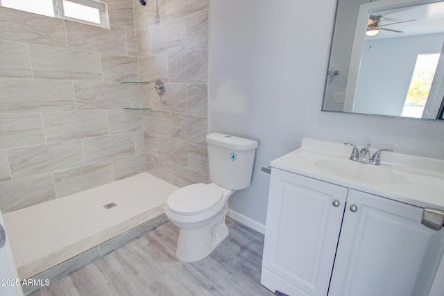 full bath with vanity, toilet, wood finished floors, and tiled shower