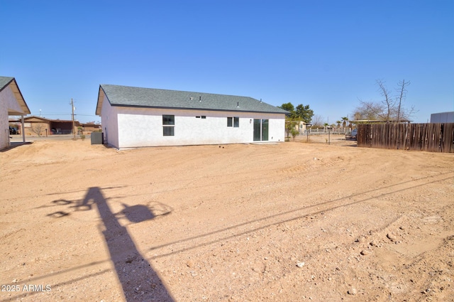 rear view of house featuring cooling unit, roof with shingles, stucco siding, and fence