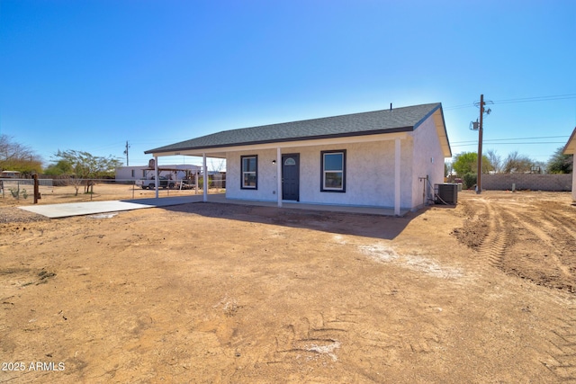 view of front of house with central air condition unit, stucco siding, roof with shingles, and fence