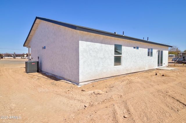 rear view of house featuring cooling unit and stucco siding