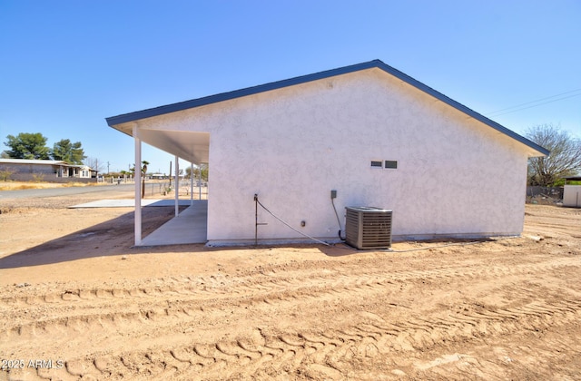 rear view of house with central air condition unit and stucco siding