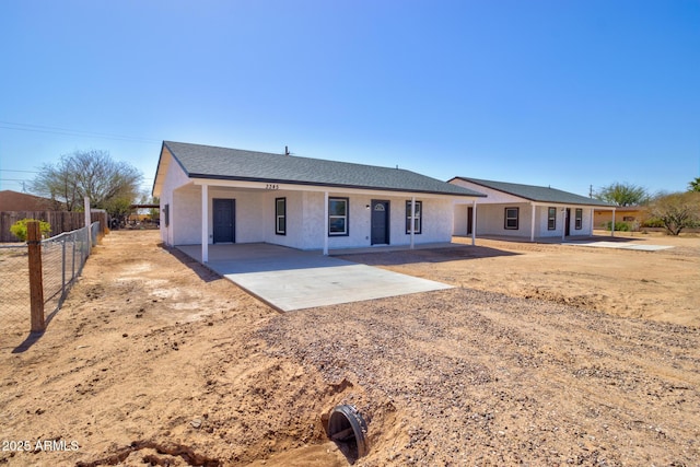 ranch-style home with a patio area, roof with shingles, stucco siding, and fence