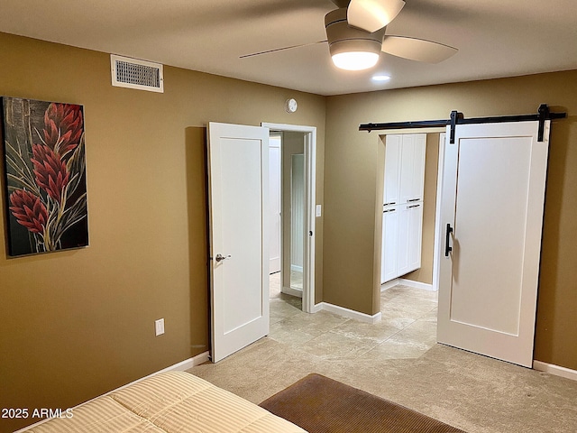 unfurnished bedroom featuring ceiling fan and a barn door