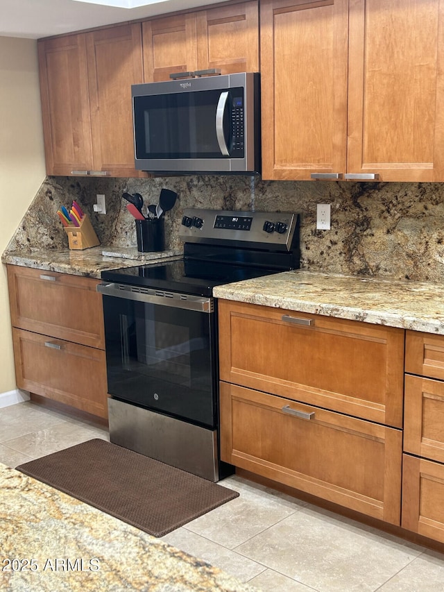 kitchen featuring decorative backsplash, light stone counters, light tile patterned floors, and stainless steel appliances