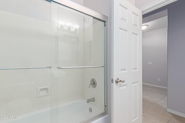 bathroom with bath / shower combo with glass door and tile patterned floors