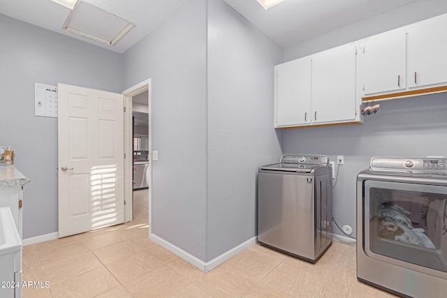 washroom with cabinets, independent washer and dryer, and light tile patterned floors