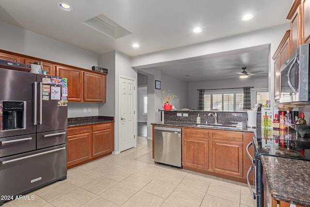 kitchen featuring dark stone countertops, appliances with stainless steel finishes, sink, and ceiling fan