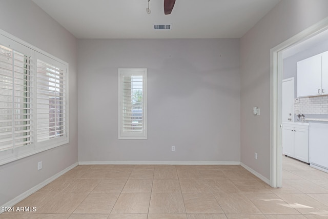 tiled empty room with ceiling fan, sink, and a healthy amount of sunlight