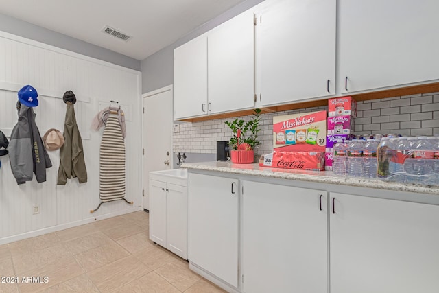 kitchen featuring backsplash, sink, light stone countertops, and white cabinets