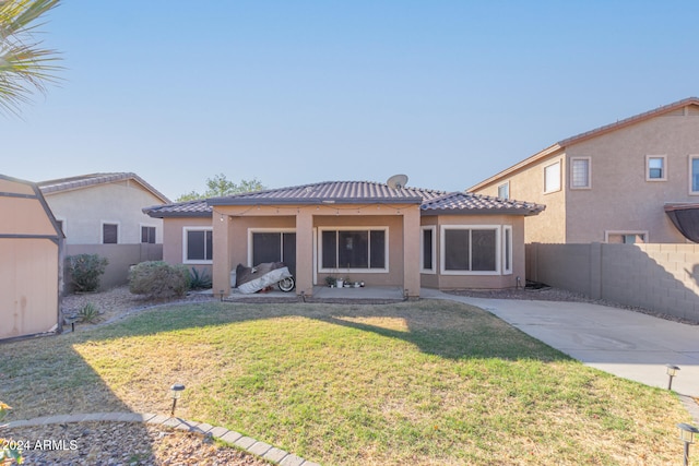 back of house featuring a storage unit and a lawn