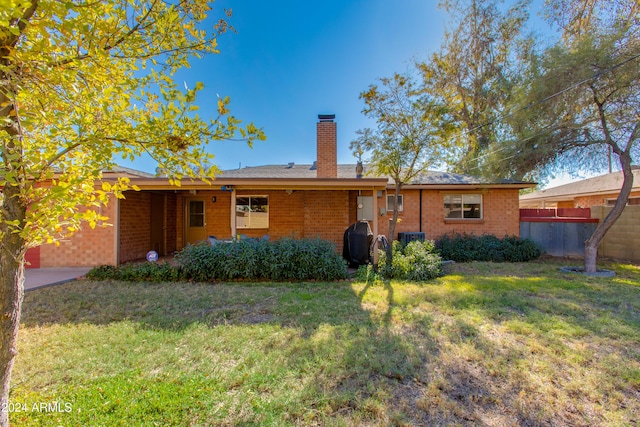 back of property with a yard and central AC unit