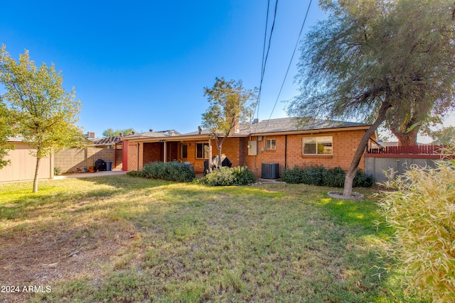 back of property with a yard and central AC