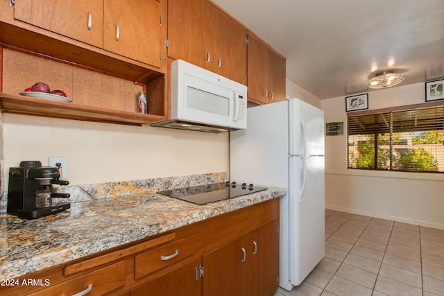 kitchen with light tile patterned floors, white appliances, and light stone countertops