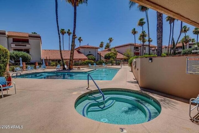 community pool with a hot tub, a patio, and fence