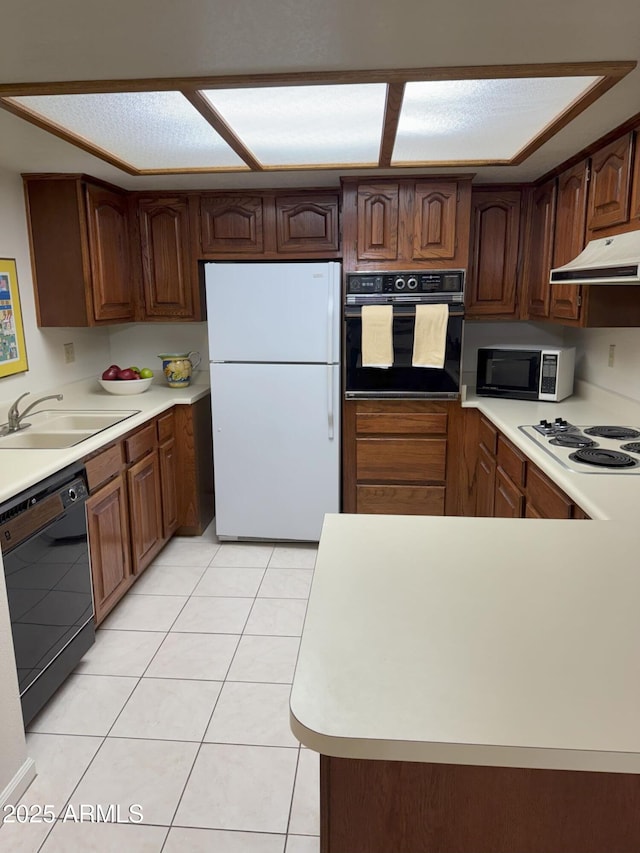 kitchen featuring black appliances, under cabinet range hood, a sink, light countertops, and light tile patterned floors