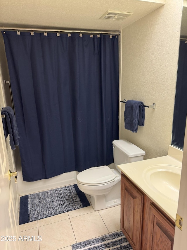 bathroom with tile patterned flooring, visible vents, toilet, a textured wall, and vanity