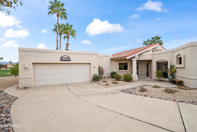 mediterranean / spanish home with stucco siding, a tiled roof, concrete driveway, and an attached garage