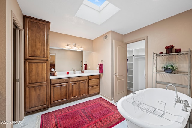 full bathroom with a soaking tub, visible vents, a skylight, and vanity