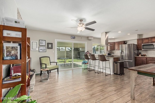 3741 W Poinsettia Dr, Phoenix, AZ 85029 - kitchen featuring stainless steel appliances, island exhaust hood, a kitchen breakfast bar, a ceiling fan, and decorative backsplash