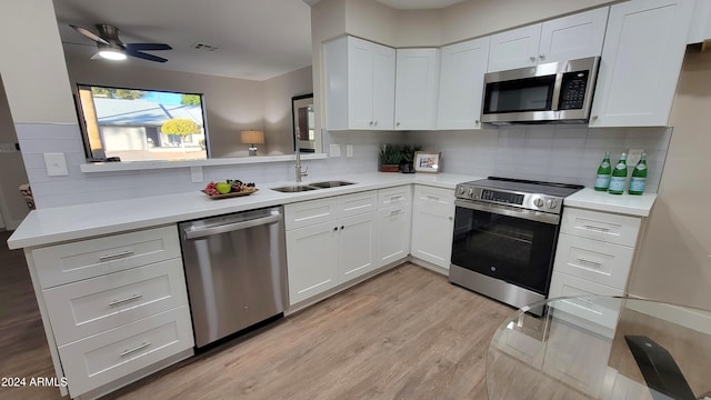 kitchen with white cabinets, sink, decorative backsplash, appliances with stainless steel finishes, and light hardwood / wood-style floors