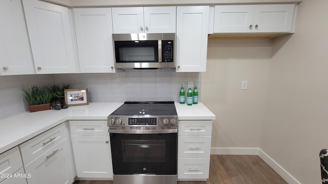 kitchen with dark hardwood / wood-style flooring, white cabinetry, appliances with stainless steel finishes, and tasteful backsplash