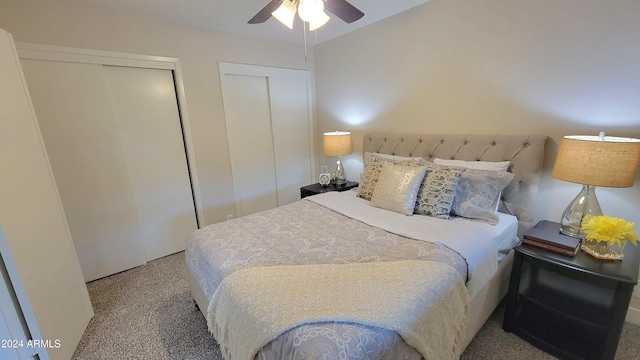 bedroom featuring ceiling fan, light carpet, and two closets