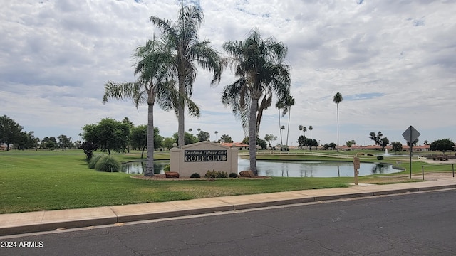 community sign featuring a yard and a water view