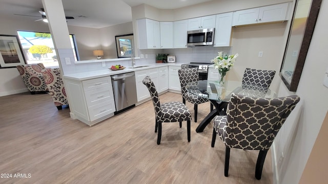 kitchen with light wood-type flooring, stainless steel appliances, white cabinetry, and tasteful backsplash