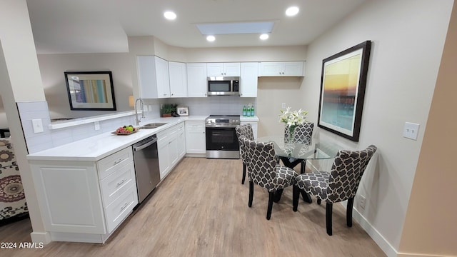 kitchen with decorative backsplash, stainless steel appliances, sink, light hardwood / wood-style floors, and white cabinetry