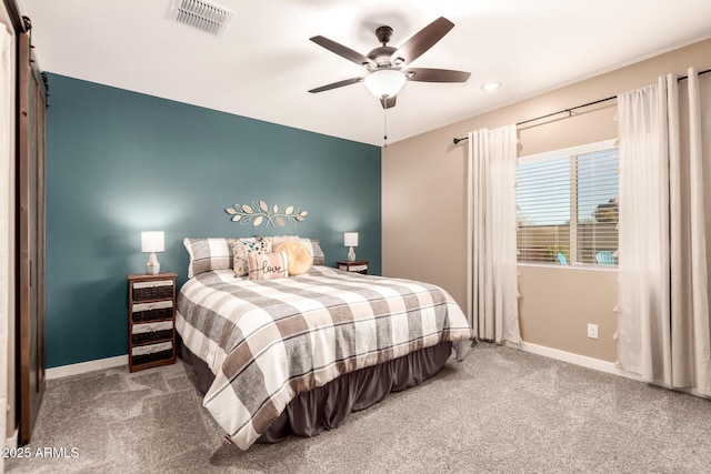 carpeted bedroom featuring ceiling fan and a barn door